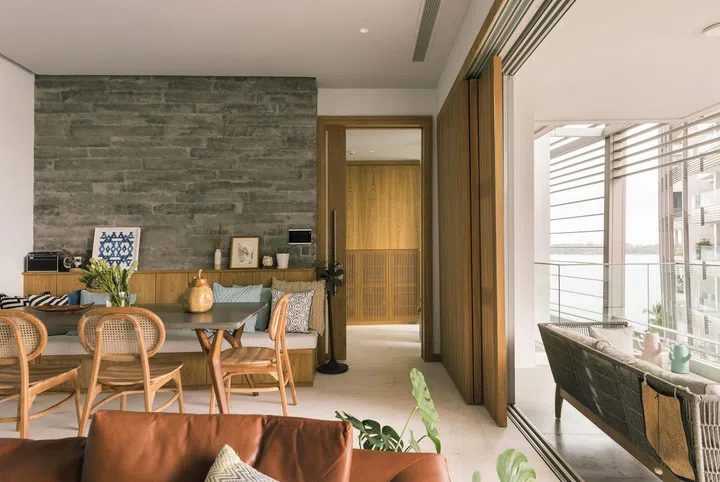 A custom dining bench, live edge dining table, and rattan chairs make the dining area in this 1,900 sq ft 3-bedroom condominium in Sentosa.