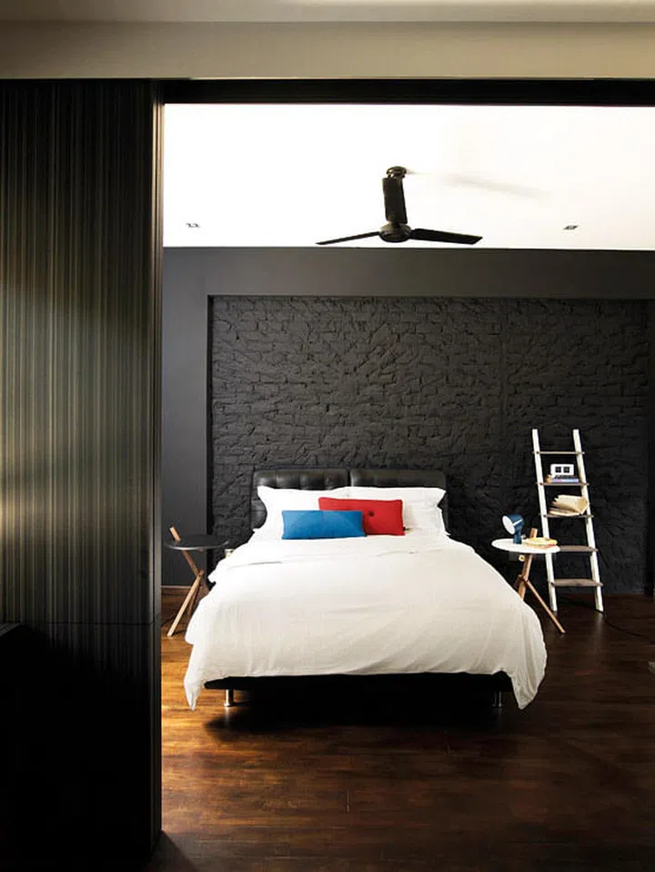The black-painted feature wall keeps the sunny master bedroom dark and cosy. Lamp from Xtra Park Mall.