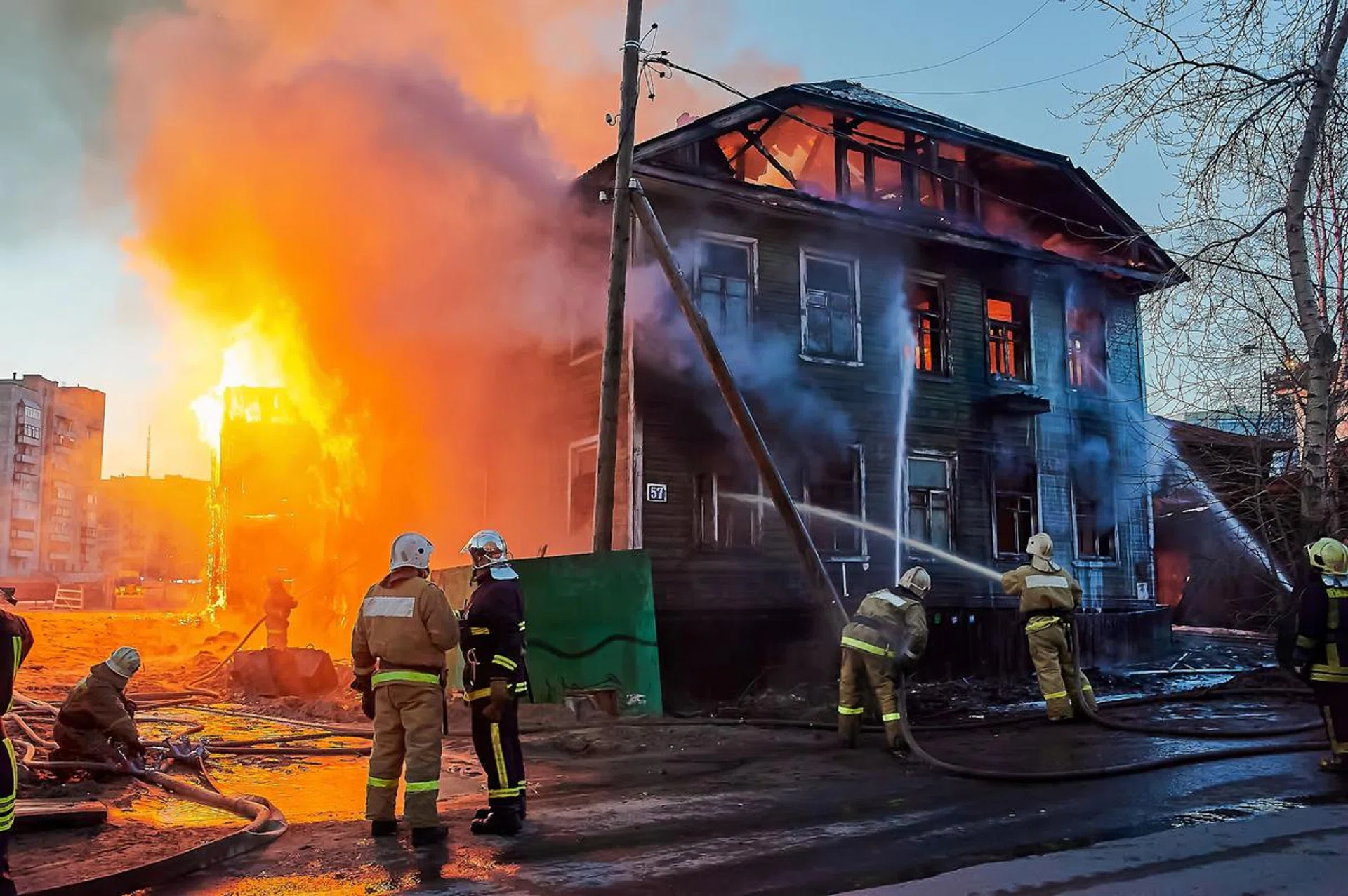 Firefighters extinguish a fire in a two-story wooden house