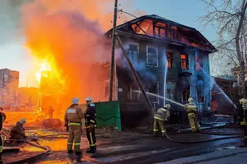 Firefighters extinguish a fire in a two-story wooden house