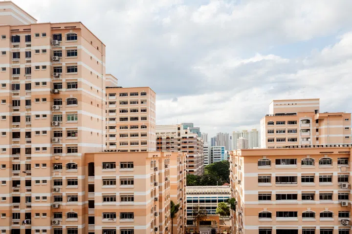A Singapore residential housing estate with apartment blocks against a cloudy sky.