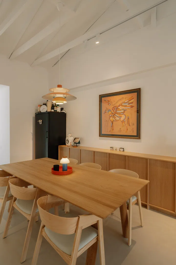 A Louis Poulsen PH 5 pendant casts a warm glow over the dining table, reinforcing the space’s role as the social heart of the home.