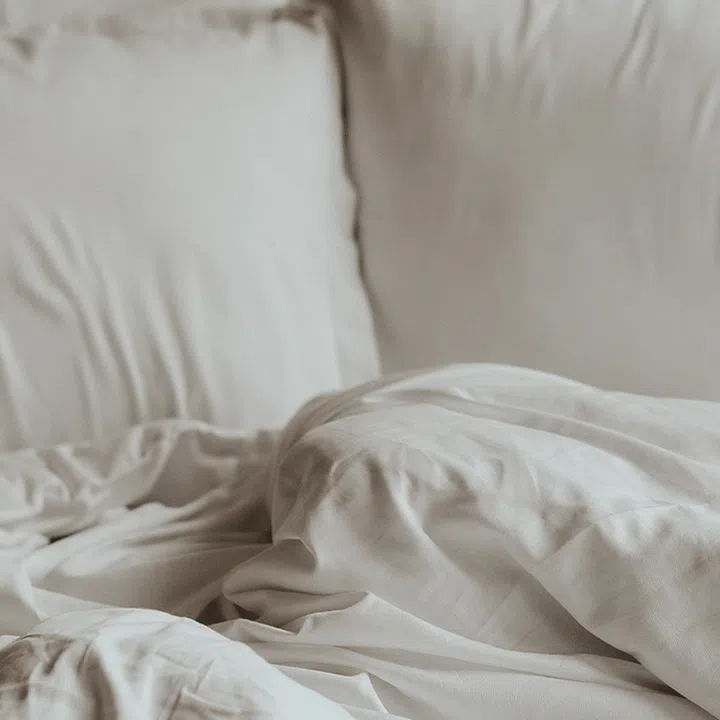 Close up of two large pillows and a duvet clad in a matching beige linen bedsheet set.