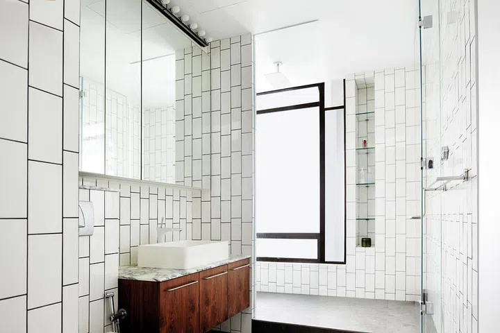 Tiles laid vertically in a brick-like pattern complement the bathroom’s stark black window frame. (Renovation cost: $350,000)