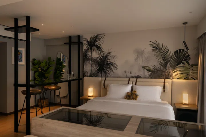 The glass bar counter and tropical mural create a calm, resort-inspired focal point in the open-plan bedroom.