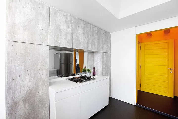 The mirror-finish stainless steel backsplash in the kitchen makes the countertop look like an island unit.