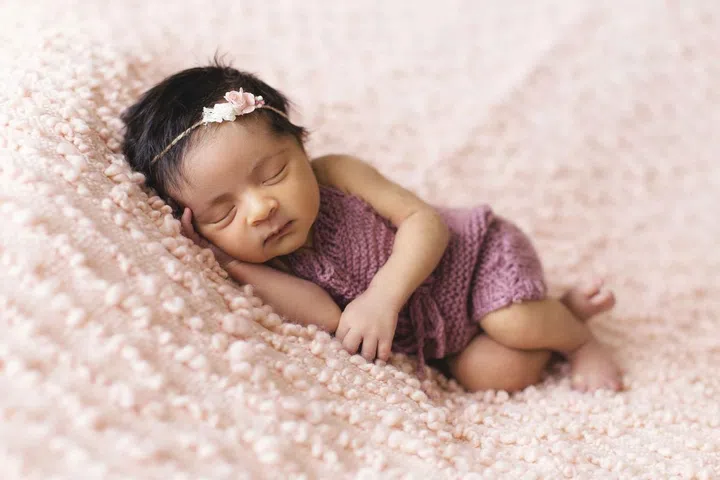 How to Sleep Better? An Ear Nose Throat Doctor Shares Expert Tips. Newborn baby sleeping soundly on a pink cushion