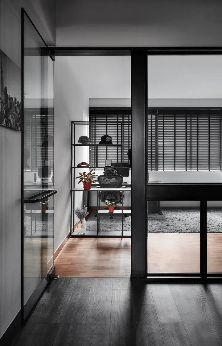 A steel-framed shelving unit creates a functional backdrop for video calls while lending the space visual depth.