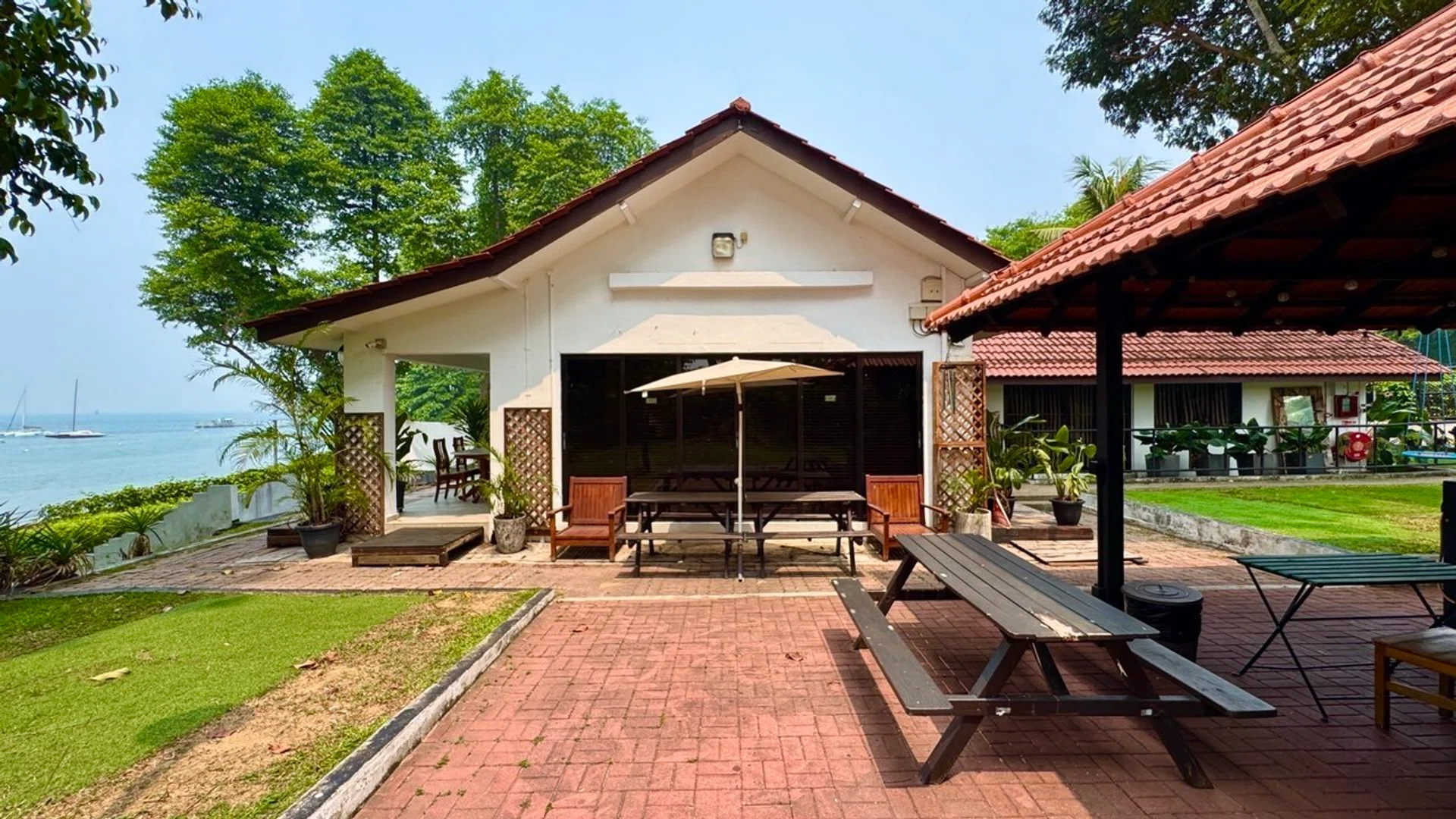 Panoramic views of the Ubin Straits frame the red-brick patio, inviting guests to gather around a repurposed BBQ pit, now a hand-built pizza oven. Features a private gate to Changi Point Coastal Walk.