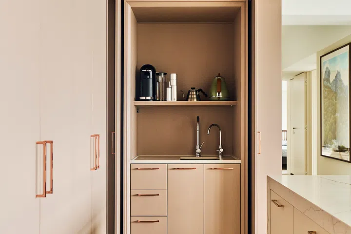 Cream, peach, and rose gold punctuate the dry kitchen.