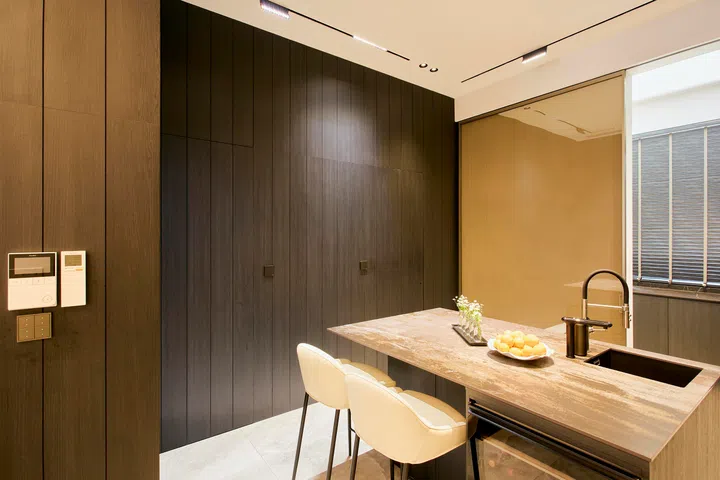 Full-height carpentry conceals appliances and storage, allowing the kitchen to read as a continuous, uncluttered volume.