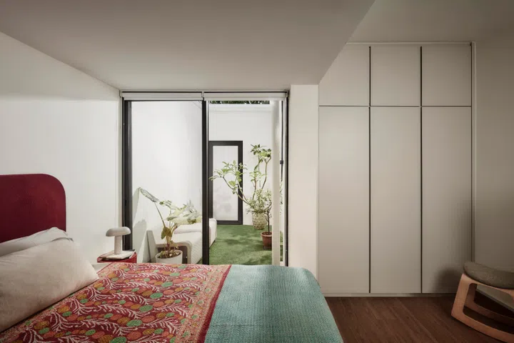 The master bedroom is kept calm and uncluttered, with soft furnishings and greenery bringing warmth into a restful, light-filled space.