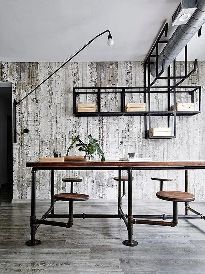 The custom-made dining table with built-in swing stools ties together the industrial look that is part edgy and part New York-loft style.