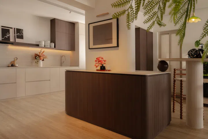 The curved kitchen island anchors the open-plan layout, designed to wrap around an immovable structural beam rather than conceal it.