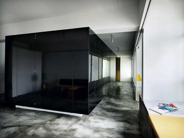 By encasing all the "unsightly" features within a home such as storage, cupboards, and an entrance to a washroom within a glossy black "box", the home is left with an uncluttered appearance that's rare in smaller apartments.