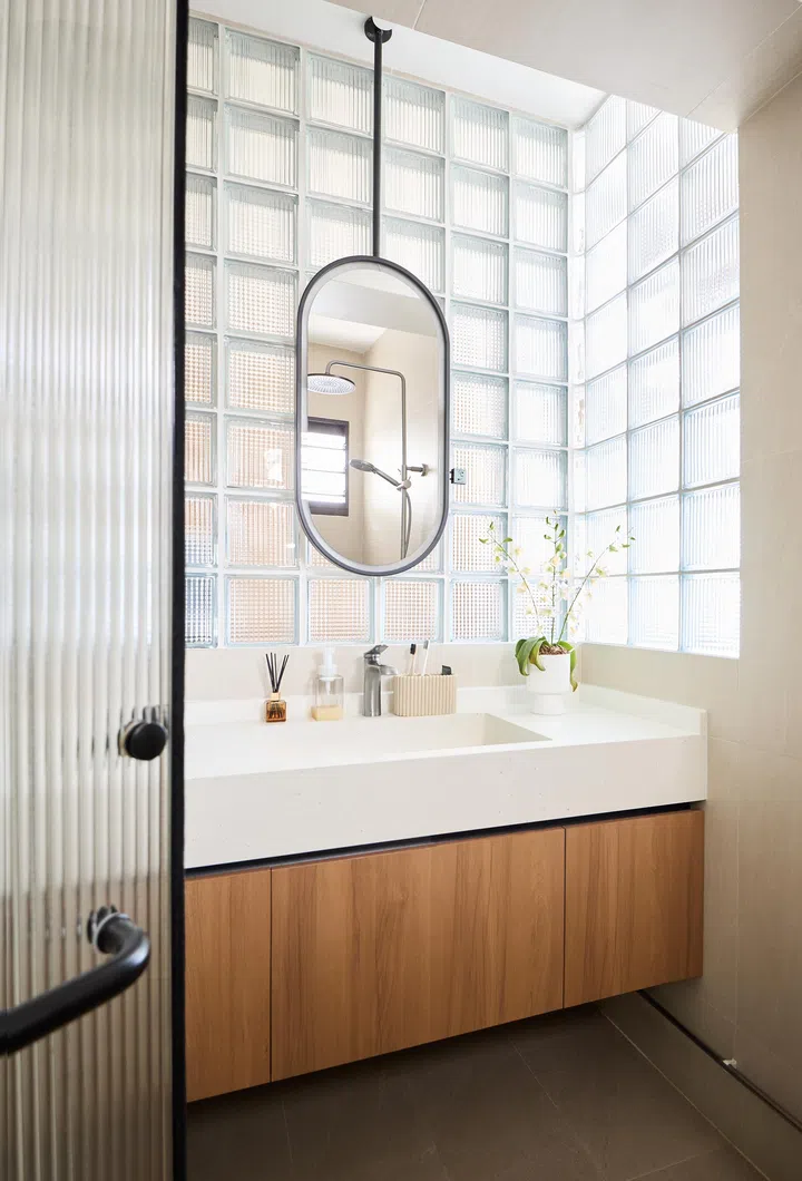Stanley converted part of the kitchen into a wardrobe, separated by sliding wood panels and the glass brick wall that diffuses natural light.