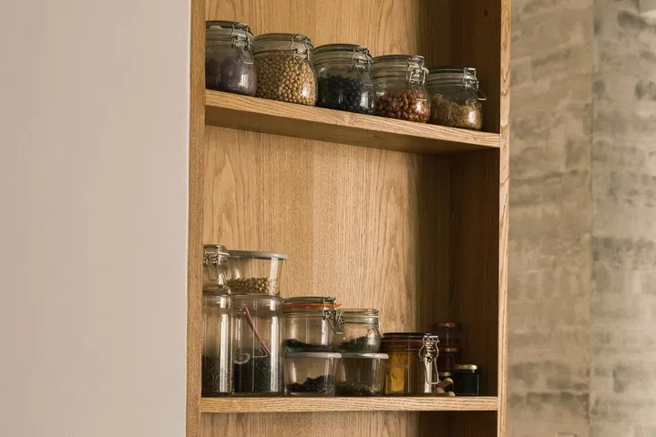 Close up of jars of condiments sitting on an open wood shelf in the kitchen of this 1,900 sq ft 3-bedroom condominium in Sentosa.