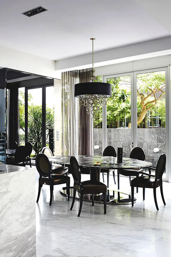 A pendant light with cascading rings balances the high ceiling with the low all-leather dining table and chairs by Fendi Casa in the dining room of a 2.5-storey bungalow in Sentosa Cove. Apart from the seaside view, you’d never guess this house sits on the beach with its ultra-luxe urban decor.