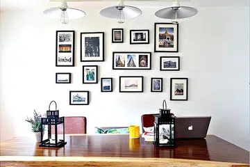 Frames of photographs on a wall behind a dining table