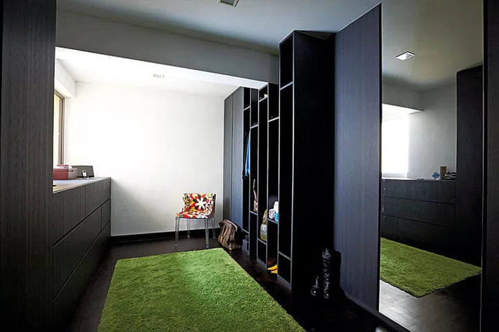 The walk-in wardrobe in this HUDC Maisonette unit in Hougang features deep drawers and full-height cabinets big enough to store the ironing board and steamer.