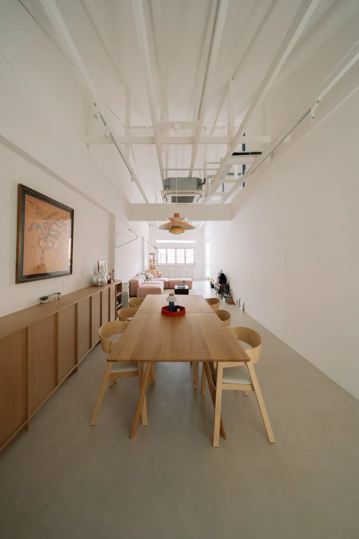 An eight-seater solid oak dining table sits beneath a Louis Poulsen pendant, while bespoke oak cabinetry, exposed roof trusses and a soaring double-volume ceiling lend the open-plan living space an airy sense of openness.