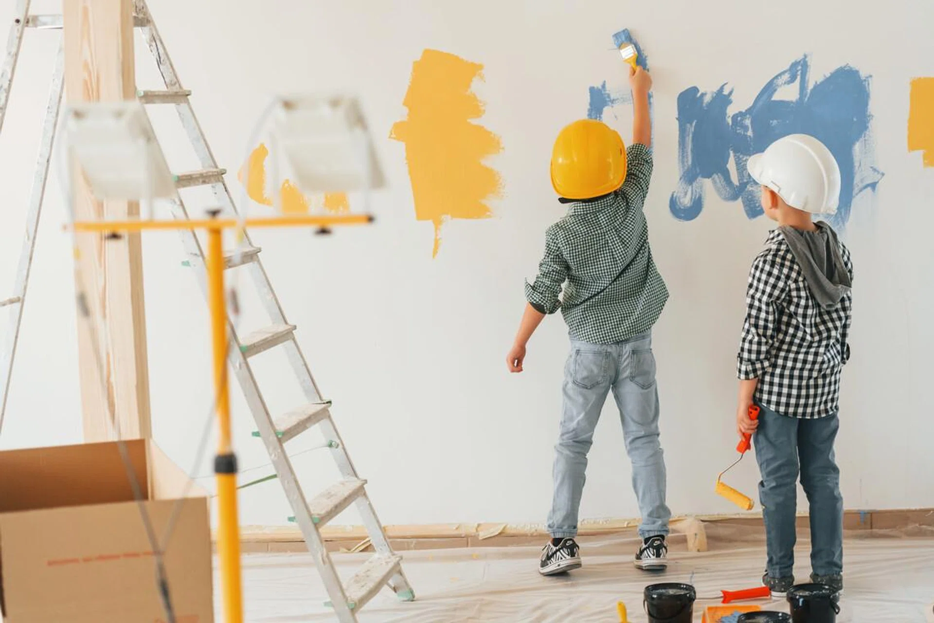 Rear view. Two boys painting walls in the domestic room.