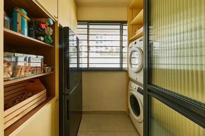 A built-in cabinet transforms the service yard into a functional extension of the kitchen, housing laundry appliances, pantry staples and the fridge.