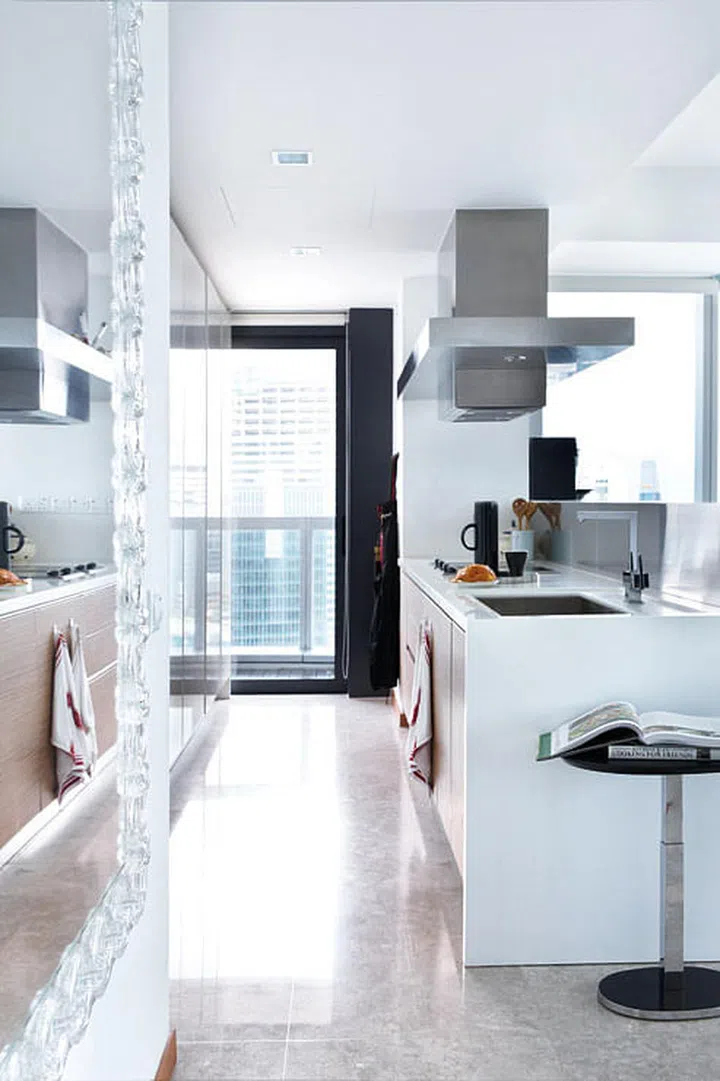 The open kitchen in this 4-bedroom Marina Bay Residences condominium allows the expat homeowners to prepare food and entertain simultaneously. A bar height counter semi-conceals the worktop and doubles as a backsplash.