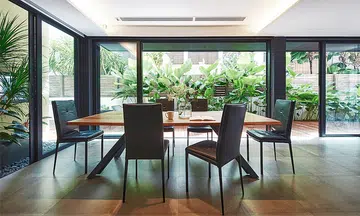 Dining room with floor-to-ceiling glass doors in this 2-storey corner terrace house in Telok Kurau designed by William Ng and Kho Keguang from Studio Wills + Architects.