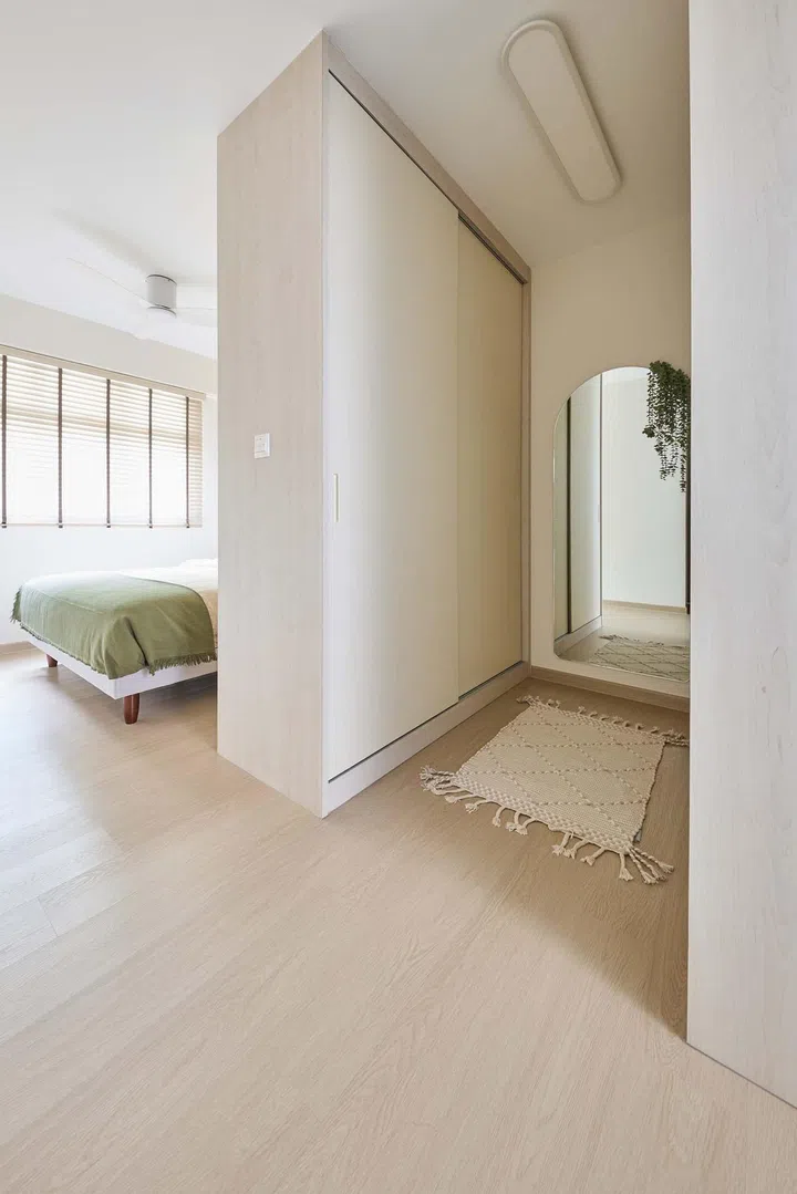 A full-height wardrobe serves as a privacy partition in the master bedroom of a minimalist 5-room HDB BTO in Tampines.