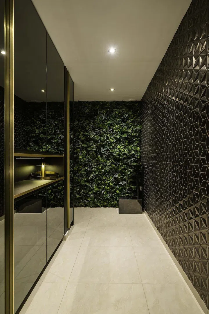 In the entrance foyer is a wall of geometric metallic tiles, and another wall finished with a smokey mirrored finish in a banking couple's 3-bedroom condominium in West Coast.
