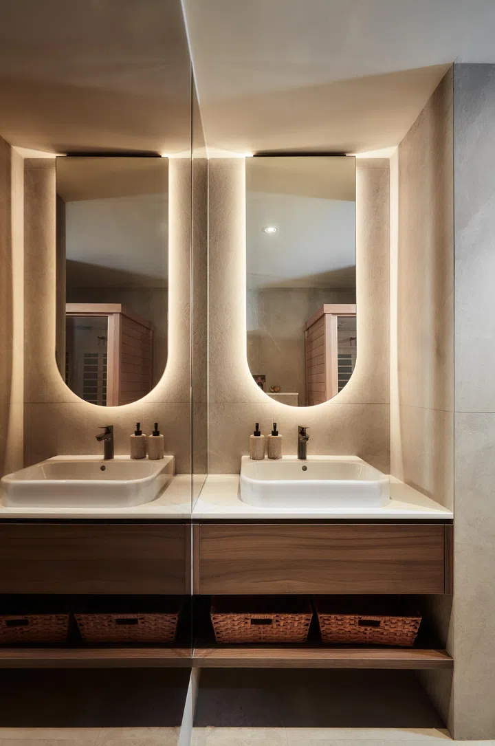 Clean lines, soft-toned tiles and strategic mirrors enhance the sense of openness in the compact powder room, balancing the warmth of the cedar sauna.