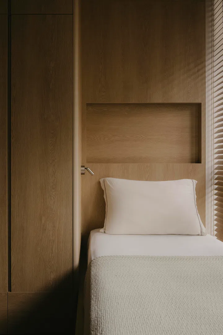 A built-in bed and concealed storage keep the guest room calm and functional, allowing it to shift easily between work and rest.