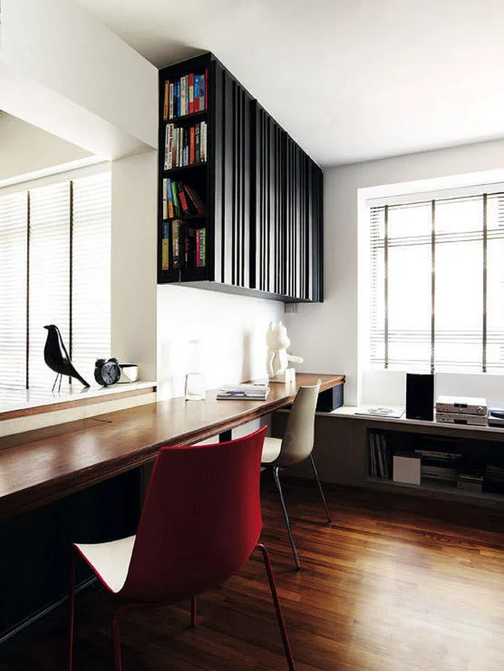 A cabinet that hangs from the ceiling uses the vertical volume of the study for storage space. The side shelves make it easy to retrieve books.