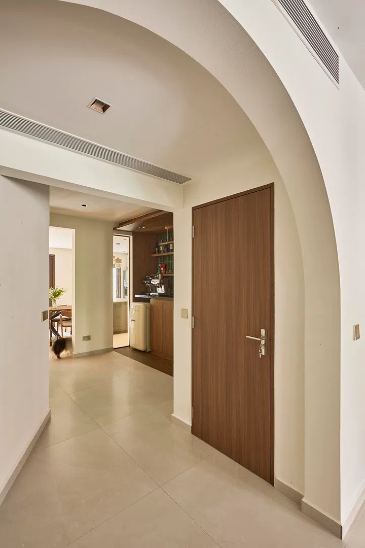An arched opening elegantly frames the transition from living to dining, with the bar tucked neatly into a recessed niche along the way.