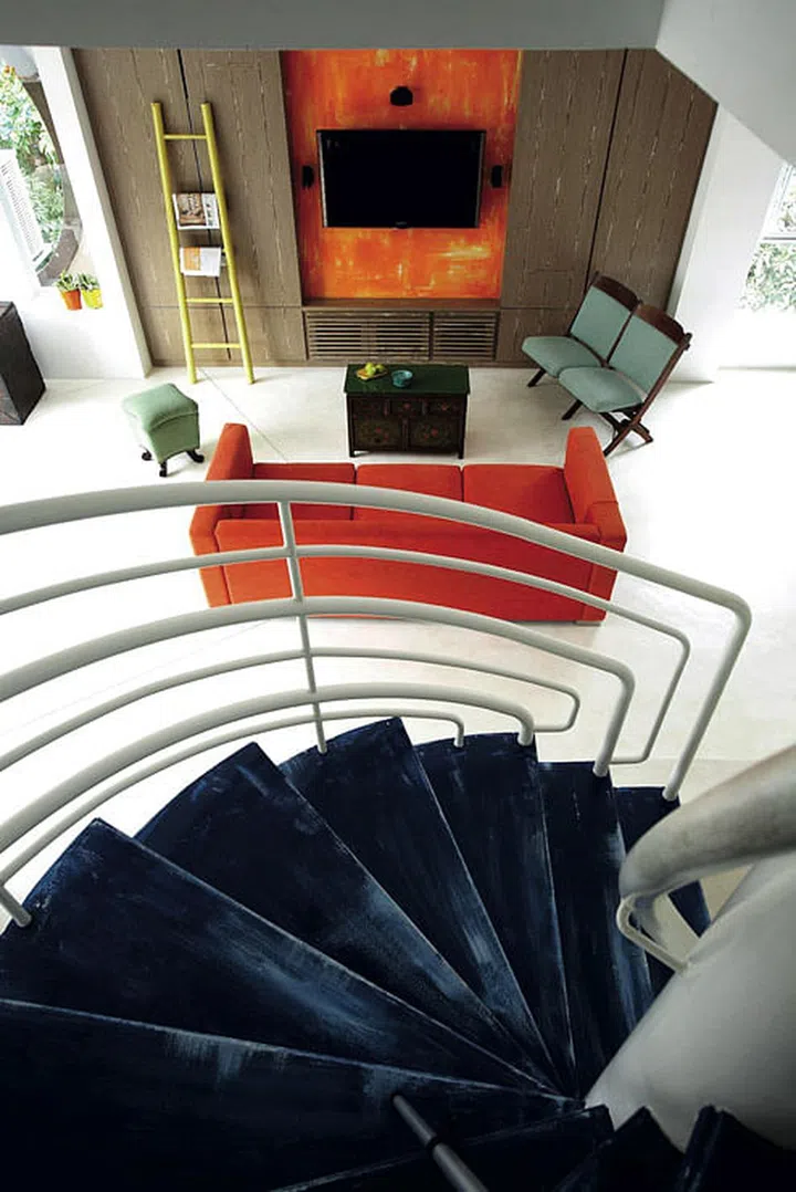 Karina created a base of clean white and pale wood tones. For a brighter ambience, she replaced the parquet flooring with lacquered white cement that looks handpainted. She also painted the stair railing white so that it blends with the walls. The blue stair treads add to the punched-up hues of the living room.