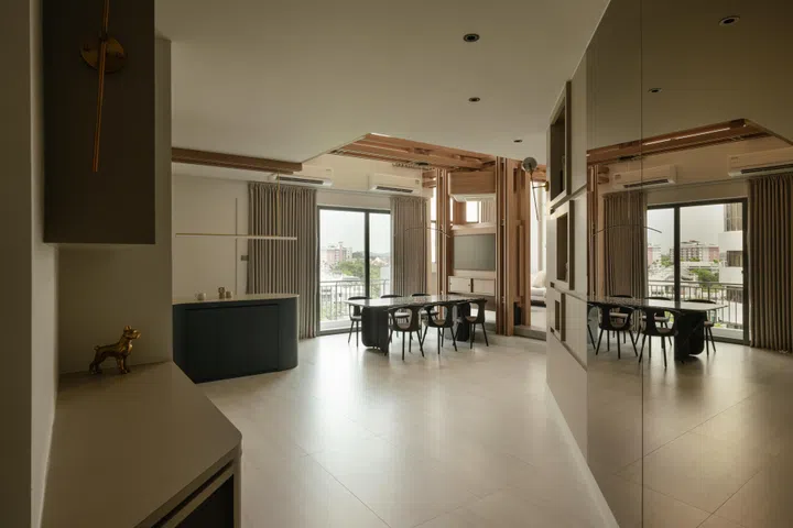 A wide entry view frames the dining area, while the living space remains partially concealed beyond the timber axis.