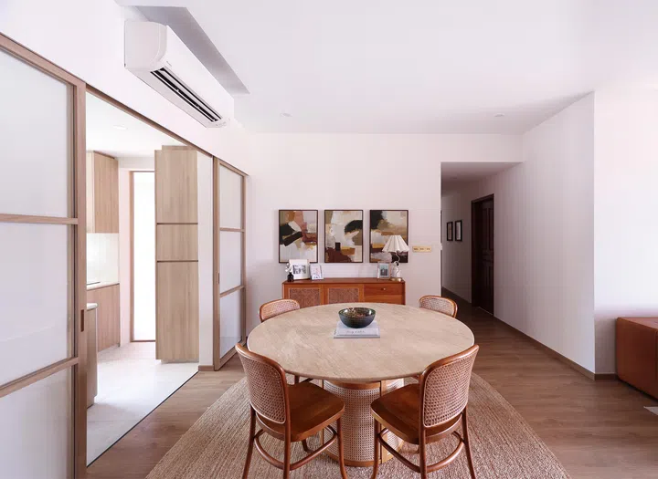 A circular dining table softens the rectilinear geometry of the interiors, while earthy artwork enhances the natural palette.