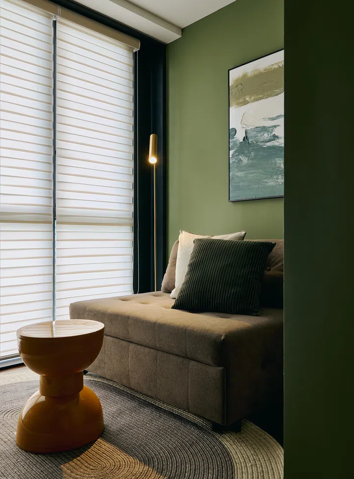 Soft green-toned walls and a pull-out sofa bed make the guest room cosy, calm, and multifunctional.