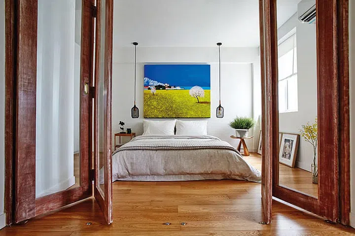 The bedroom has a restful feel and is kept simple with a low bed, white walls and warm wood-tone flooring.