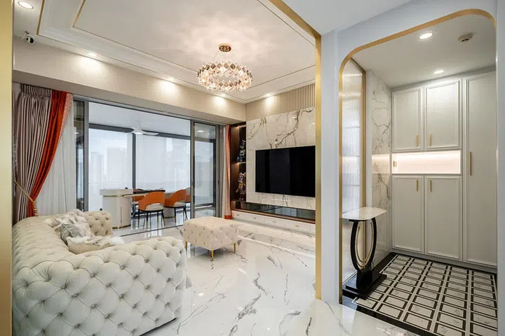 The focal point of the space is a lavish marble TV feature wall, adorned with intricate gold trimmings that evoke the essence of modern rococo style.