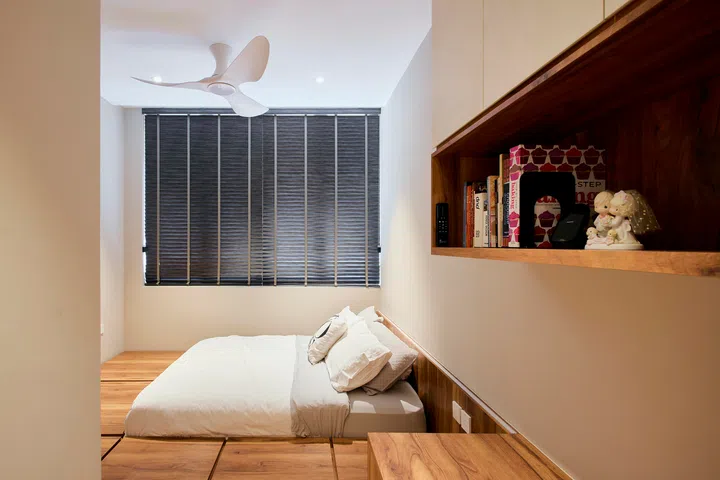 A low platform bed and integrated shelving keep the room pared back, with warm timber tones softening the space.