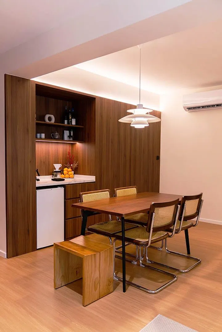 The dining area is anchored by a wooden table and modern dining chairs, with rattan accents that add warmth and texture to the space.