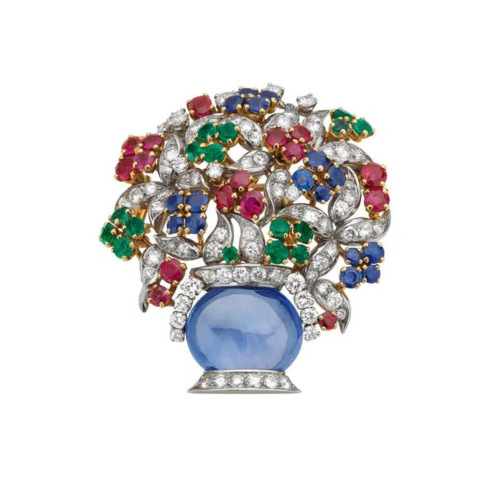 "Giardinetto" brooch in gold and platinum with sapphires, emeralds, rubies and diamonds, 1960.
The vase formed of an oval cabochon sapphire on a diamond-set stand, the foliage suggested by leaf-shaped diamond pave set motifs, the flower-heads decorated with circular-cut emeralds, rubies and sapphires.  Marks: on the mount, at the base of the vase: "BVLGARI" engraved.