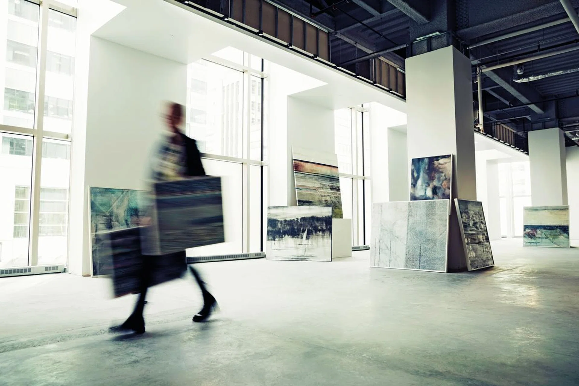 16 Apr 2015 --- Art dealer walking with paintings in art gallery --- Image by © Hero Images/Corbis