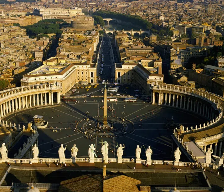 The monumental wings which flank the sides of the oval shaped Piazza San Pietro were designed by Bernini in the 17th century. The border between Vatican City and Rome is where the long avenue leading out the square begins. | Location: Border of Vatican City and Rome. View from: Dome. --- Image by © Free Agents Limited/CORBIS