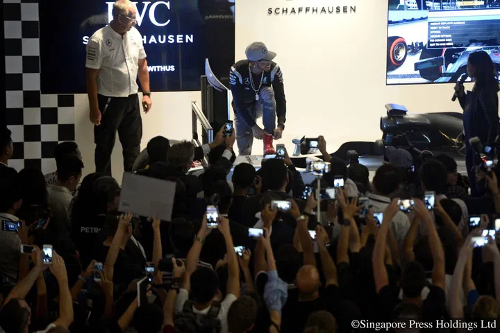 Three-time Formula One champion Lewis Hamilton tying his laces on stage after driving a race-car simulator during his public appearance at Marina Bay Sands on 14 September 2016.