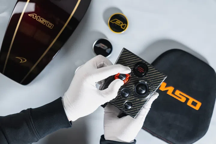 A gloved artisan carefully fits a button by hand, highlighting the precision craftsmanship behind McLaren Special Operations bespoke detailing.