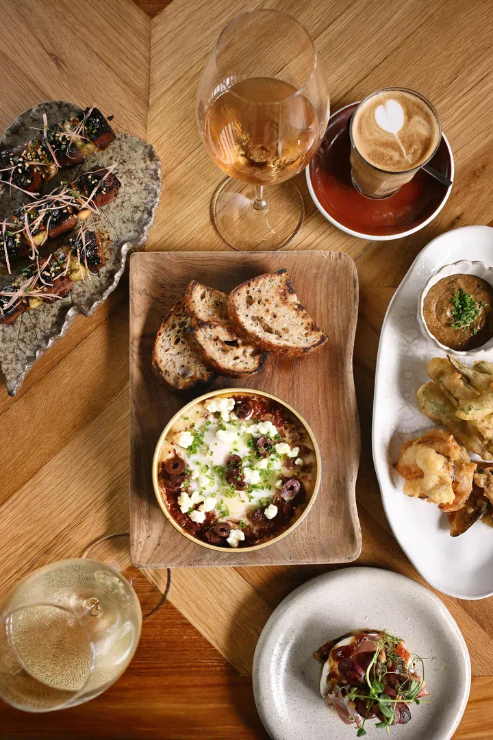 Open Farm Community 餐桌俯拍图，桌上摆放多道适合分享的料理，包括搭配烤面包的蘸酱、前菜小盘、炸物以及葡萄酒与咖啡，呈现以自然食材为主、适合好友聚会的用餐场景。| 新加坡最值得打卡的高颜值聚餐好去处