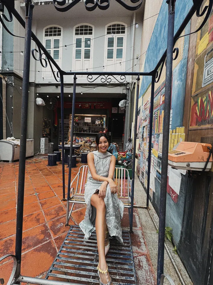 符芳榕穿着银灰色长裙，坐在复古铁制秋千上，背景是彩绘老建筑。符芳榕，命运使者，离开演艺圈，专访